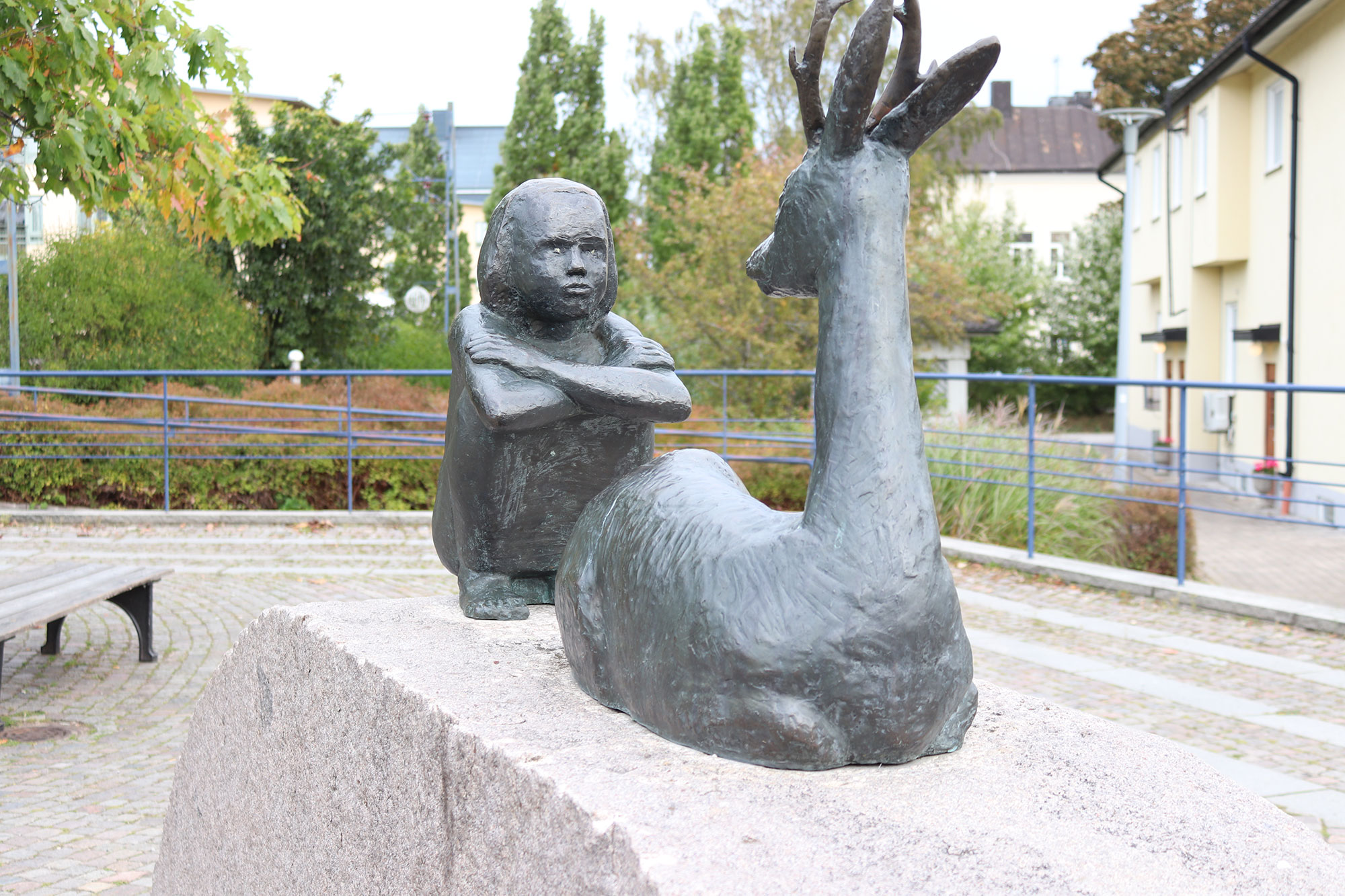 Staty i brons av en flicka som sitter på huk och ett rådjur
